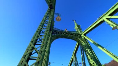 BUDAPEST, HUNGARY - 23 Şubat 2022: Macar Arma Paltosu ile süslenmiş tarihi Özgürlük Köprüsü boyunca tramvay yolculukları, Turul kuşları kulelerin tepesinde ve klasik sokak lambaları, Budapeşte, Macaristan