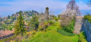 Ortaçağ taşı Castello di San Vigilio surlarının panoraması, çiçek açan bahar bahçesi ve arka planda Monte Bastia, Bergamo, İtalya