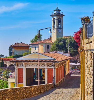 Walk down Via al Castello on San Vigilio Hill and observe the upper station of Bergamo-San Vigilio funicular and San Vigilio Church with tall bell tower in background, Bergamo, Italy clipart