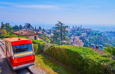 The beautiful landscape from the top of San Vigilio Hill, observing Bergamo-San Vigilio funicular, hazy planes, lush trees and the skyline of medieval Bergamo, Italy clipart