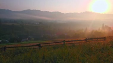 Ovanın sisli panoramik manzarası. Arka planda dağların siluetleri ve gündoğumu güneşi, Dzembronia, Karpatlar, Ukrayna