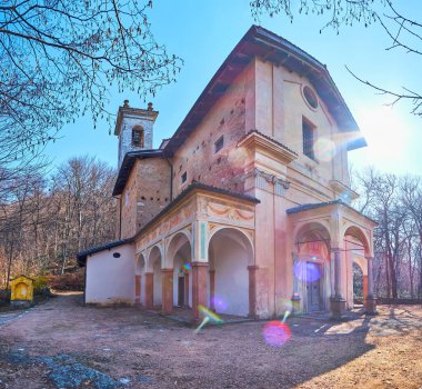 Panorama of the medieval Madonna d'Ongero Sanctuary with lens flare effect, Carona, Ticino, Switzerland clipart