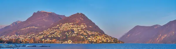 stock image Ceresio lakeside promenade opens a perfect view on the Monte Bre, Monte Boglia and Monte Sighignola in bright sunset light, Lugano, Switzerland