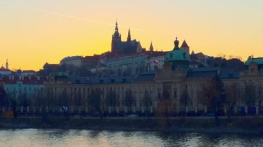Vltava Nehri 'nin karanlık suları, Straka Akademisi ve St Vitus Katedrali' nin silueti altın günbatımı gökyüzüne karşı, Prag, Çek