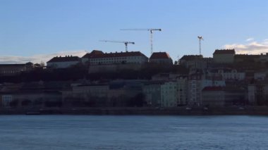 Budapeşte, Macaristan 'ın başkenti Budapeşte' de Tuna Nehri 'nin seti boyunca uzanan tarihi evler, kiliseler ve balıkçıların kalesi üzerinde Buda Kalesi' nin günbatımı manzarası.