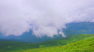 Panoramic landscape of green mountains of Chornohora Range with swirling fluffy clouds from the peak of Mount Hoverla, Carpathians, Ukraine