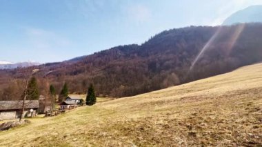 Alp yamacında, çayırda ve modern taşta küçük taş evleri olan Panorama San Giovanni Battista Kilisesi, Mogno, Valle Maggia, Ticino, İsviçre