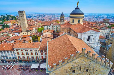 İtalya 'nın arka planında Bergamo Katedrali ve Gombito Kulesi kubbesi olan Palazzo della Ragione' nin çatısı ve siperleri.