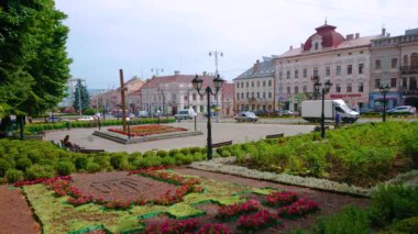 CHERNIVTSI, UKRAINE - 16 Temmuz 2021 'de Çernivtsi' de tarihi yapıların yer aldığı Central Square 'de gölgeli ağaçlar ve çiçek açan çiçeklerle dolu güzel yeşil bahçe