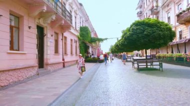 CHERNIVTSI, UKRAINE - 16 Temmuz 2021: Çernivtsi 'de tarihi yaya panoraması, rengarenk tarihi malikaneleri, küfleri, restoranları, kafeleri, dükkanları ve süslü akçaağaç ağaçlarıyla temizlenmiş Olha Kobylyanska Caddesi