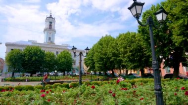 CHERNIVTSI, UKRAINE - 16 Temmuz 2021: Belediye binası ve çiçek açan kırmızı güllü yeşil bahçeli Central Square Panorama
