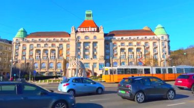 St Gellert Meydanı 'nda yoğun bir trafik var. Güzel, taştan bir kaynak evi ve Budapeşte, Macaristan' daki Gellert Spa Oteli 'ne karşı.