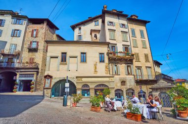 Bergamo, İtalya 'daki Piazza Mercato delle Scarpe adlı eski kasaba evlerinin önündeki küçük açık hava restoranı.