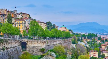 The flowering park at the foot of Venetian Walls of Bergamo and the old houses of the upper town (Citta Alta), Italy clipart