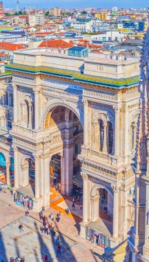 MILAN, ITALY - APRIL 8, 2022: Triumphal Arch the main entrance portal to Galleria Vittorio Emanuele II with the rooftops of Milans city center in the background, on April 8 in Milan clipart