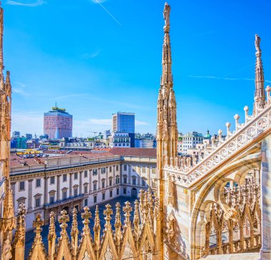 View on Palazzo Reale di Milano and Torre Velasca tower through the spires of Milan Cathedral, Italy clipart