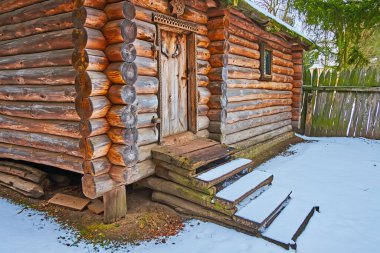 The snowy yard of the old Slavic estate with a facade of the living timber house and tall palisade, Pereiaslav Scansen, Ukraine clipart