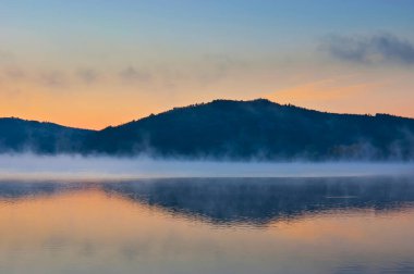 Mladost Gölü 'nün buharlı suları, tepelerin, Veles' in, Kuzey Makedonya 'nın karanlık siluetlerini gölgeliyor.