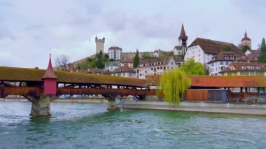 Arka planda, Maria auf der Reuss ve Reuss-Nadelwehr (Needle Barajı) Köprüsü Şapeli ile süslenmiş ikonik ahşap Spreuerbrucke (Spreuer Köprüsü) ile Reuss Nehri 'nin panoramik manzarası,