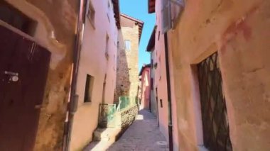 Ortaçağ sokağı, taştan evlerle dolu olup, Carona, Ticino, İsviçre 'deki Piazza della Chiesa (Kilise Meydanı)' nda yer alan Santi Giorgio e Andrea (Aziz George ve St Andrew) kilisesine çıkar.