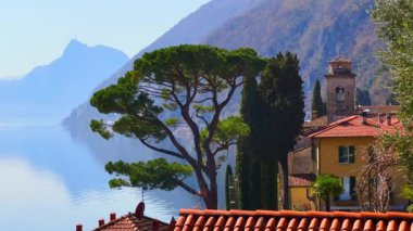 Oria 'daki Lugano Gölü' nün pitoresk setinden San Salvatore 'un puslu kaygan kayganlaştırıcısı. Uzun selvi ağaçları ve San Sebastiano Kilisesi, Valsolda, İtalya' nın ortaçağ çağ çanları.