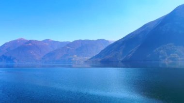 Lugano Gölü kıyısında yürüyün ve güzel dağ manzaralarını, gölün mavi dalgalı yüzeyini, Monte dei Pizzoni 'nin kayalık zirvesini ve İtalya' nın Valsolda kentinin küçük köylerini gözlemleyin.