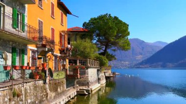 Lugano Gölü, San Mamete, Valsolda, İtalya kıyısındaki renkli vintage evler ve yemyeşil ağaçlar.