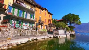 Lugano Gölü 'ndeki iskeleden San Mamete panoraması, renkli göl evleri, küçük tekneler, dalgalı göl yüzeyi ve karşı kıyıdaki dağlar, Valsolda, İtalya