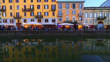 Naviglio Grande Kanalı 'nın setindeki canlı yaşam, akşam ışıklarını ve küçük açık hava kafeleri olan renkli evleri yansıtıyor, Milano, İtalya