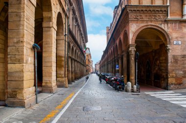 Via Zamboni street with parked bikes along arcades of Basilica of San Giacomo Maggiore, Bologna, Italy clipart