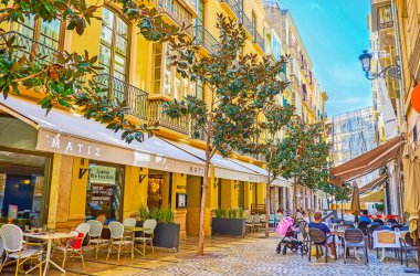 Malaga, İspanya - 26 Eylül 2019: 26 Eylül 'de Malaga' da uzun ağaçları ve açık hava restoranlarıyla dar gölgeli Sancha de Lara Caddesi