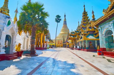 Kuzey sokağı, Shwedagon Pagoda 'ya gidiyor, çatıları, şemsiyeleri, aynaları ve oyulmuş duvarları olan muhteşem tapınaklarla çevrili, Yangon, Myanmar