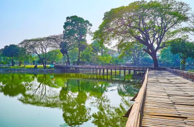 Gölün üzerindeki sallanan kereste köprüsü Kandawgyi parkının yerel cazibesidir, Yangon, Myanmar