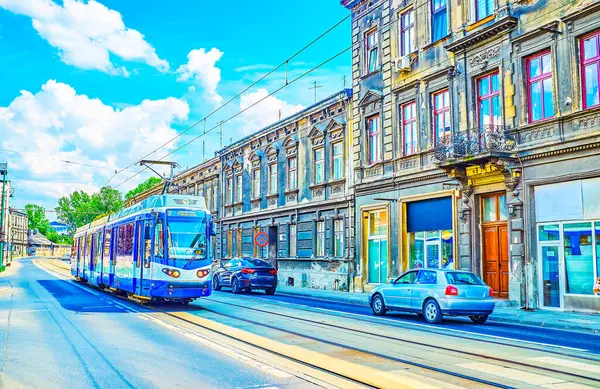 Podgorze bölgesindeki Boleslawa Limanowski caddesi boyunca uzanan mavi tramvay, Polonya 'nın Krakow kentindeki eski yapılarla dolu.