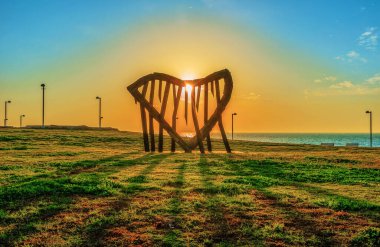 TEL AVIV, ISRAEL - 25 Şubat 2016: Charles Clore deniz kenarı şehir parkında gün batımı, batan güneş Ilan Averbuch tarafından heykel aracılığıyla görülüyor, adı Harp the Sea and the Quiet Wind, Tel Aviv, İsrail