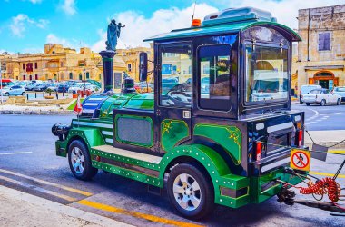 Eski tarz eğlence treni turistleri St. Joseph anıtı ve Malta 'nın Rabat kentindeki tarihi konutlarla birlikte Rabat Müzesi' nin meydanında bekliyor.