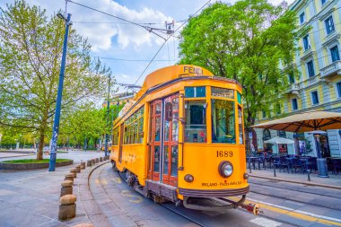 MILAN, ITALY - 8 Nisan 2022: 8 Nisan 'da İtalya' nın Milano kentinde, Piazza Sempione 'deki klasik tramvay turları yerel restoranların sevimli açık hava teraslarından geçiyor.