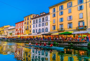 MILAN, ITALY - 08 Nisan 2022: 8 Nisan 'da İtalya' nın Milano kentinde, Naviglio Grande 'deki şehir ışıklarının yansımaları arasında kanal boyunca yavaşça süzülür.