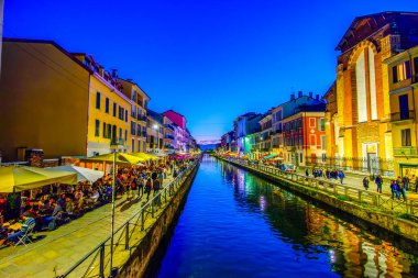 MILAN, ITALY - 08 Nisan 2022: Akşam çökerken, yerel halk ve turistler 8 Nisan 'da İtalya' nın Milano kentinde Naviglio Kanalı boyunca gezintiyi paylaşıyorlar.