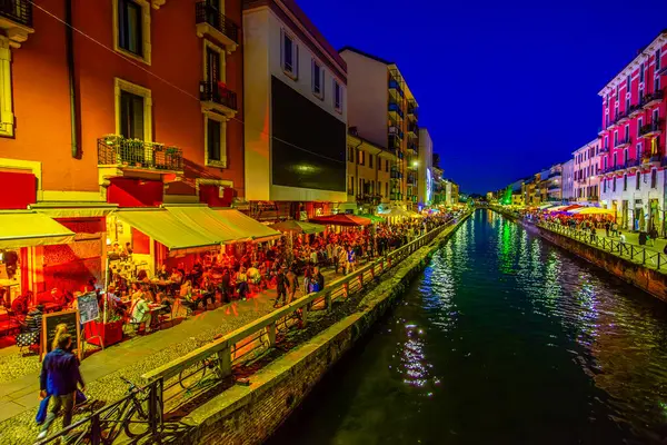 MILAN, ITALY - 08 Nisan 2022: Akşam çökerken, yerel halk ve turistler 8 Nisan 'da İtalya' nın Milano kentinde Naviglio Kanalı boyunca gezintiyi paylaşıyorlar.