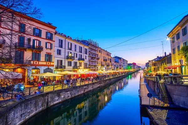 MILAN, ITALY - 08 Nisan 2022: Akşam çökerken, yerel halk ve turistler 8 Nisan 'da İtalya' nın Milano kentinde Naviglio Kanalı boyunca gezintiyi paylaşıyorlar.