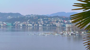 The hazy view of the port on Lake Lugano and the mountains behind it from the slope of Monte Bre, Ticino, Switzerland