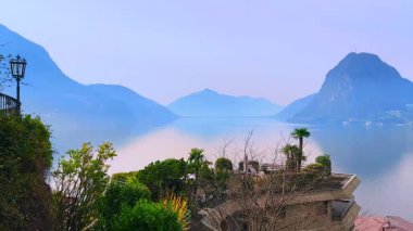 Lugano Gölü 'nün önündeki Monte Bre yamacındaki yemyeşil çatı bahçesi ve sisli Alp yamaçları, Ticino, İsviçre