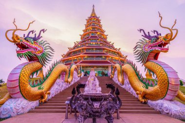 Altın Phop Chok Dhamma Chedi alacakaranlık gökyüzünde zarafetle ve simetriyle parıldıyor, Tayland dini mimarisinin özünü yakalıyor, Wat Huai Pla Kang, Chiang Rai, Tayland