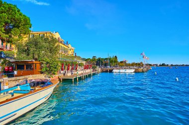 Sirmione 'nin feribot iskelesinden gelen parlak mavi Garda Gölü' nün dalgalı yüzeyi, İtalya 'nın göl kıyısında farklı konteynırların bayraklarını sallıyordu.