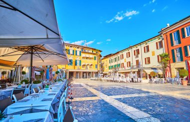 Büyük yaya Piazza Giosue Carducci, İtalya 'nın Sirmione kentindeki yerel kafe ve restoranların renkli binaları ve teraslarıyla dolu.