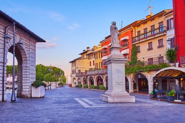 Giuseppe Malvezzi Meydanı 'ndaki Sant' Angela anıtına karşı renkli evler ve günbatımı gökyüzü, Desenzano del Garda