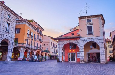 Eski turist Piazza Giuseppe Malvezzi meydanında, renkli evleri, hediyelik eşya dükkanları ve açık hava restoranları olan Desenzano del Garda, İtalya 'nın tadını çıkarın.