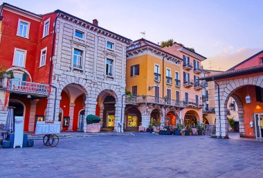 İtalya 'nın Desenzano del Garda kentindeki tarihi konutları, açık hava restoranları ve dükkanlarıyla Giuseppe Malvezzi Meydanı akşam manzarası