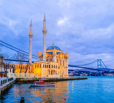 Ortakoy Camii, İstanbul, İstanbul 'daki İstanbul Köprüsü' nün yüksek açıklığı altında akşam ışığında parlıyor